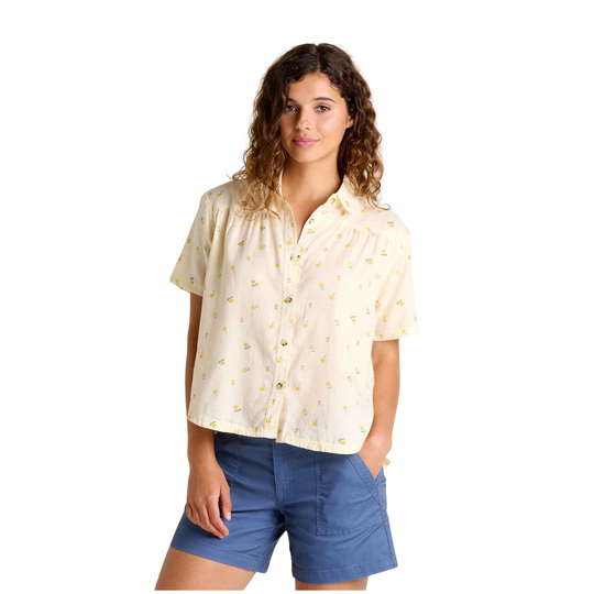 Woman wearing a light-colored blouse with a subtle pattern and blue shorts on a white background