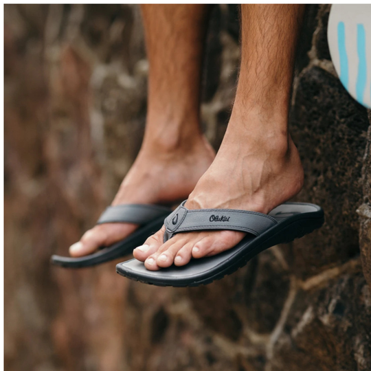 Person wearing black sandals on a stone surface