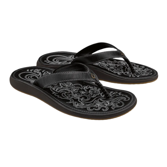 Black sandals with intricate white patterns on a white background