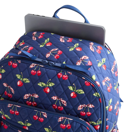 Navy blue backpack with cherry pattern containing a laptop on a white background