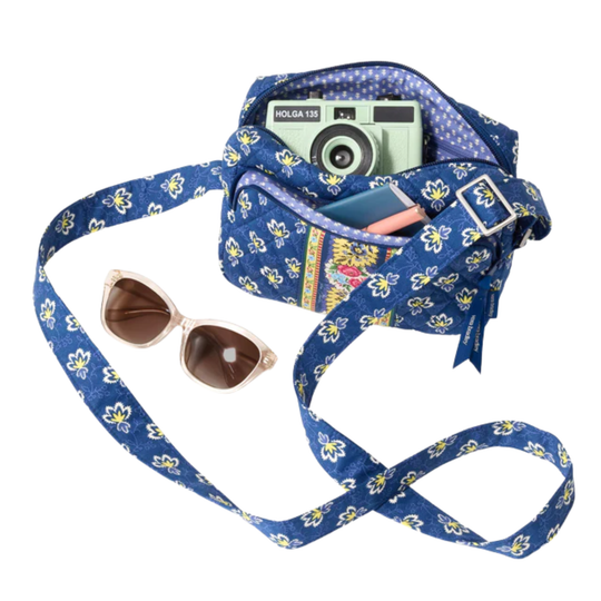 Blue floral-patterned camera bag with a camera, sunglasses, and other items on a white background