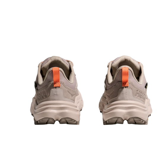 Pair of beige hiking shoes with orange accents on a white background