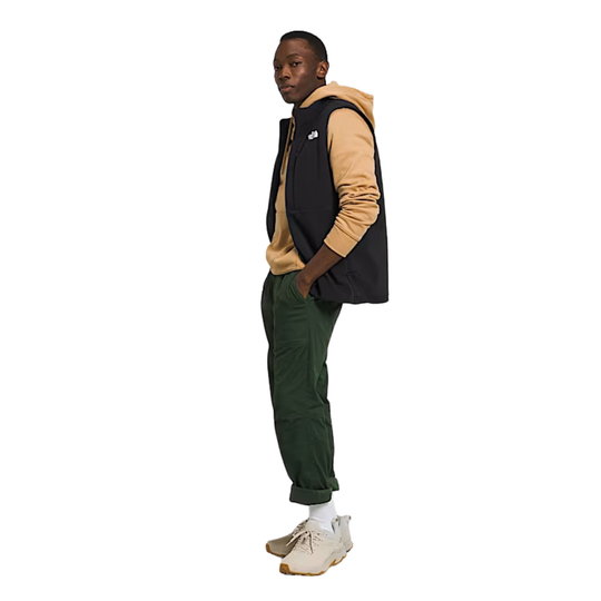 Man wearing a black and beige jacket with green pants on a white background