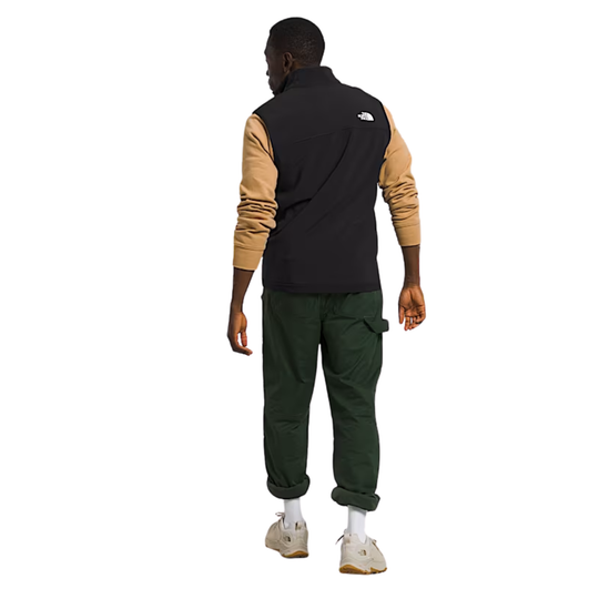 Person wearing a black and tan jacket with green pants on a white background