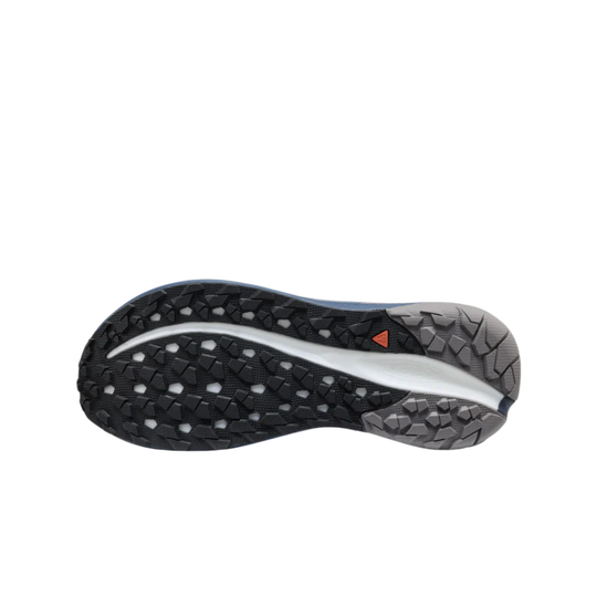 Trail running shoe outsole in black and gray with a white curved midfoot section and a small orange triangle mark