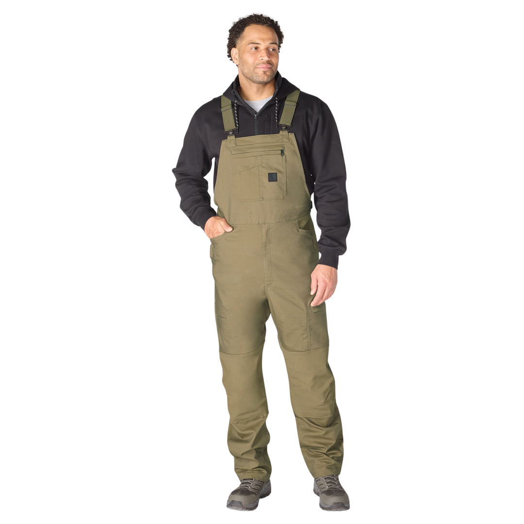 Man wearing a black shirt and green bib overalls on a white background
