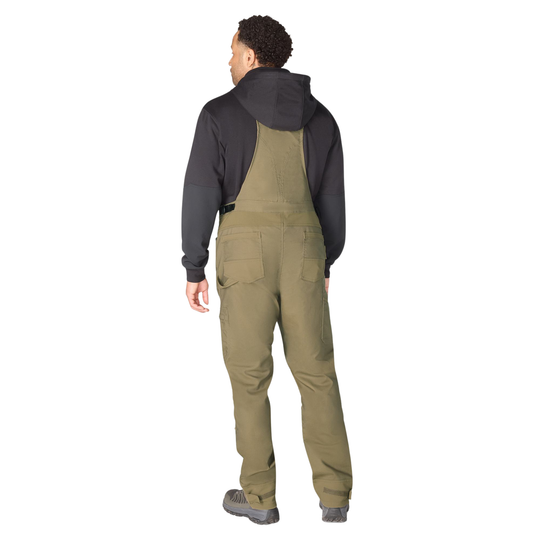 Man wearing a black shirt and green bib overalls on a white background