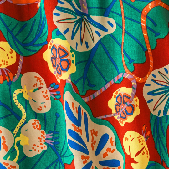 Colorful fabric with abstract floral and leaf patterns on a red background