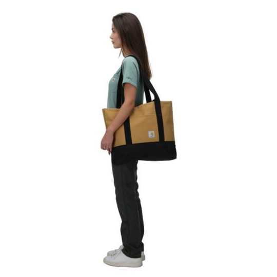 Person holding a black and beige tote bag on a white background