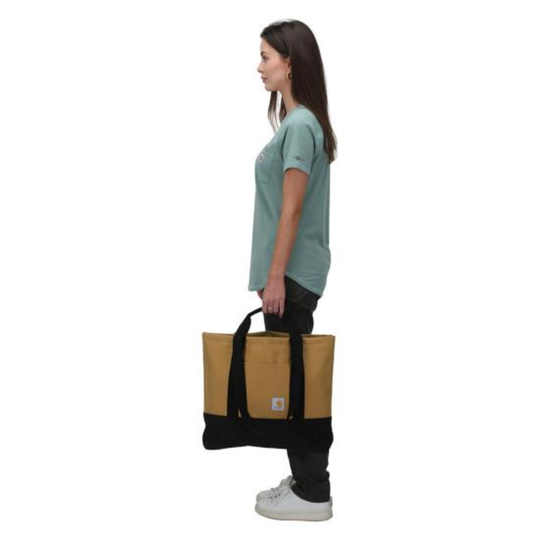 Woman carrying a black and tan tote bag on a white background