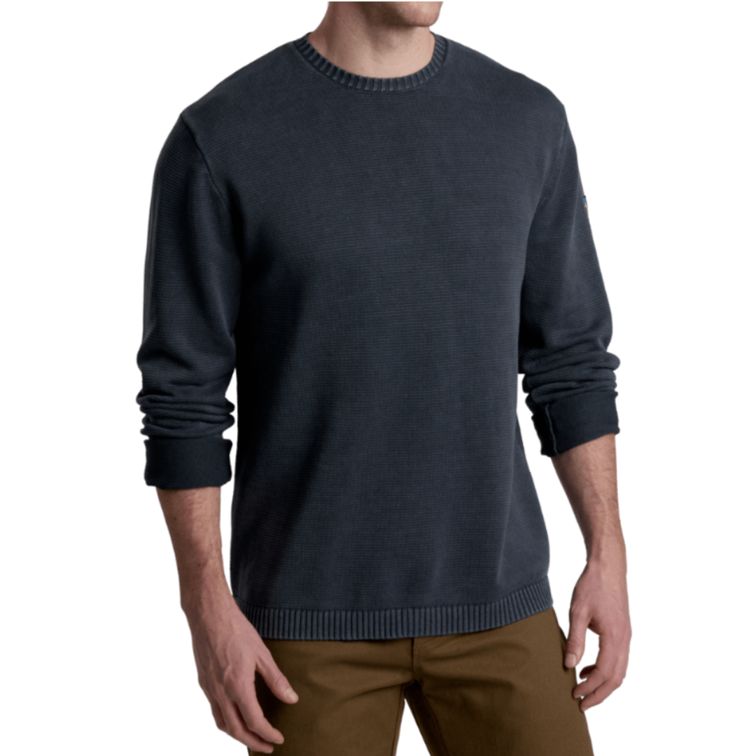 Man wearing a dark blue sweater and brown pants on a white background