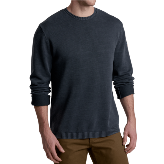 Man wearing a dark blue sweater and brown pants on a white background