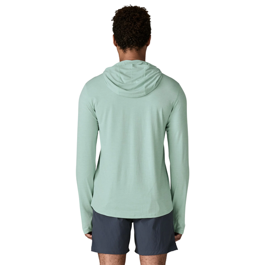 Person wearing a light green hoodie and dark shorts on a white background