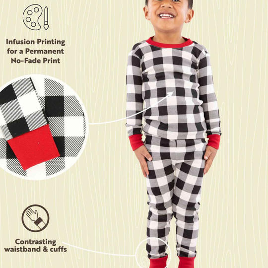 Child wearing black and white checkered pajamas with red accents on a beige background.
