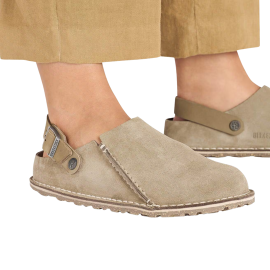 Beige suede shoes worn with beige pants on a white background