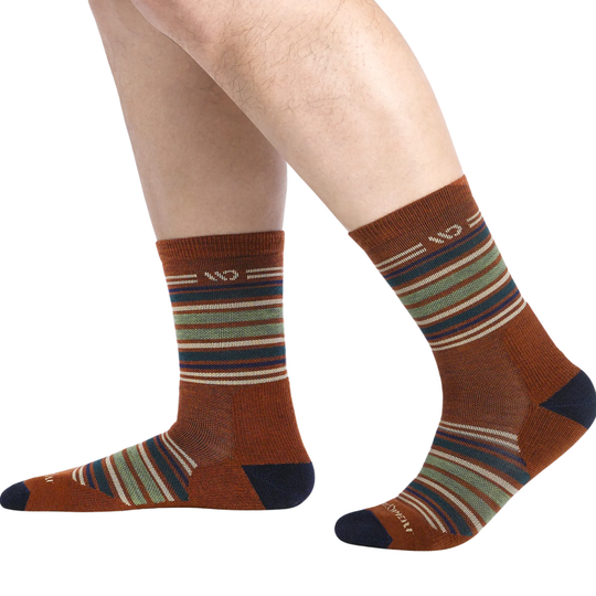 Striped socks with brown, green, and blue pattern worn by a person on a white background