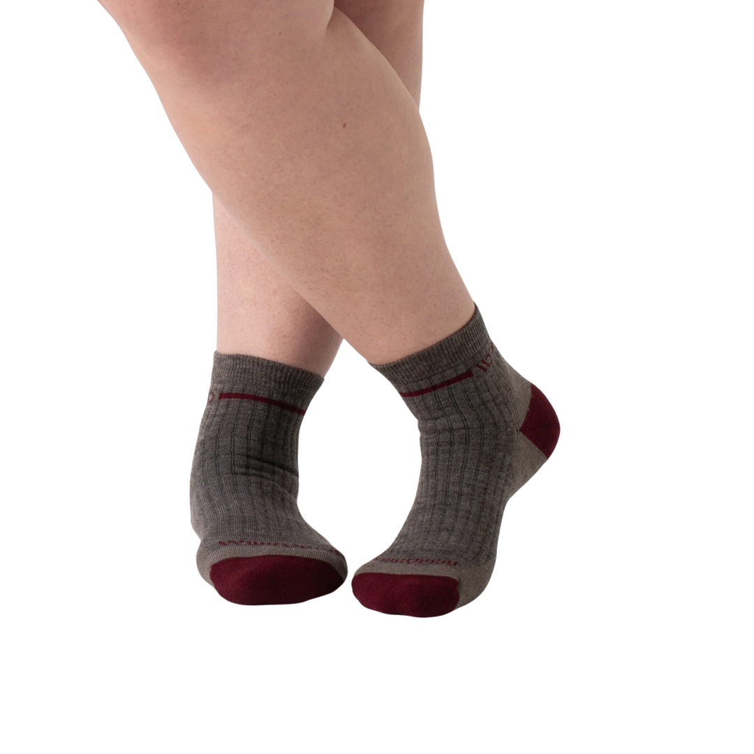 Gray socks with red toes and cuffs worn by a person on a white background