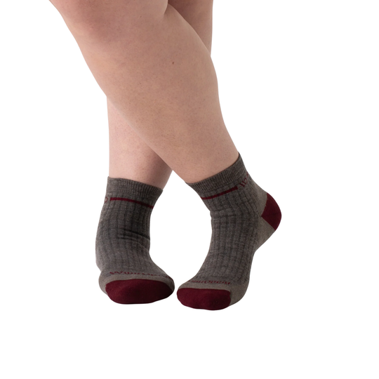 Gray socks with red toes and cuffs worn by a person on a white background