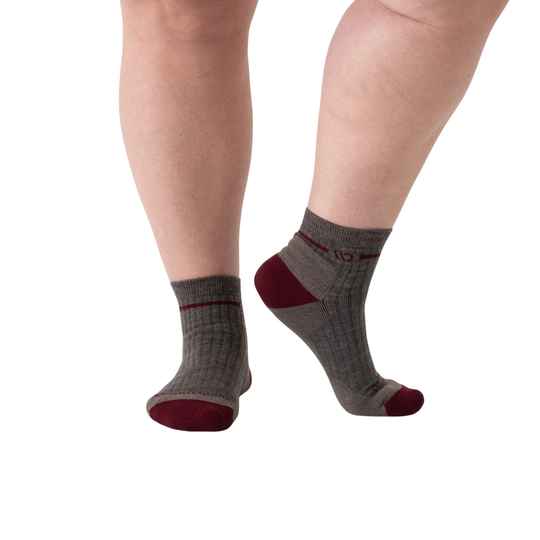Gray socks with red accents worn by a person on a white background