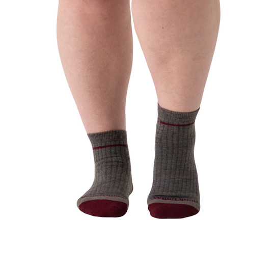 Gray socks with red accents worn by a person on a white background