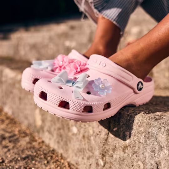 Pink clog shoes on a grey curb side street 