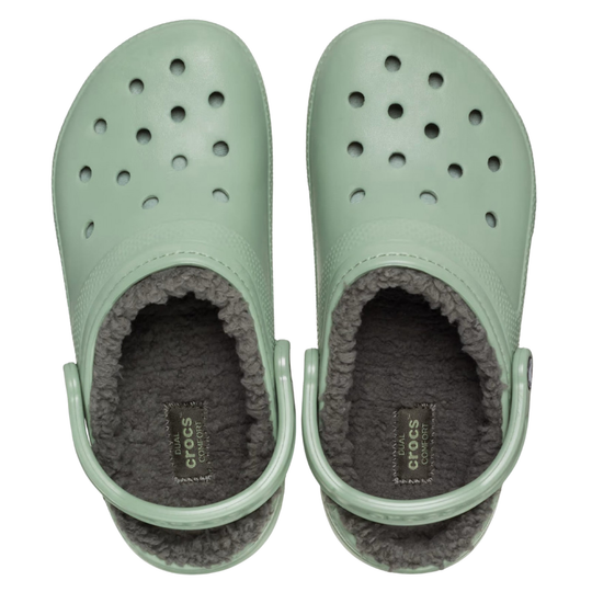 Pair of light green clogs with gray fur lining on a white background