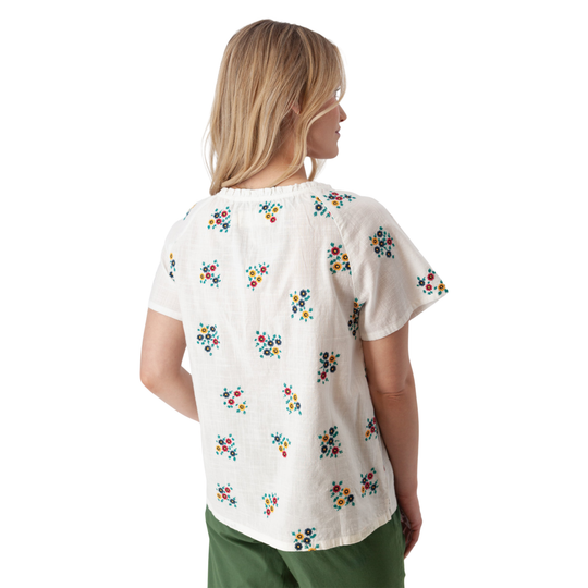 Woman wearing a white blouse with colorful floral patterns on a white background