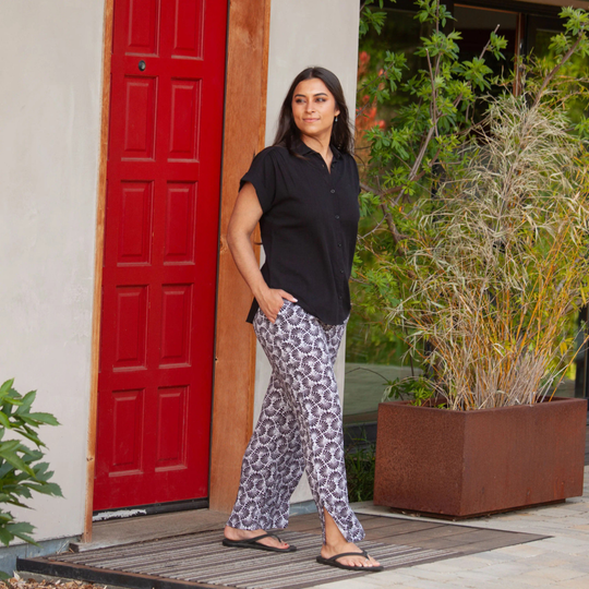 Woman standing in front of a red door with plants around