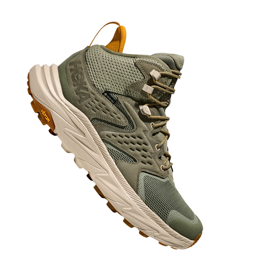Green hiking boot with white sole on a white background