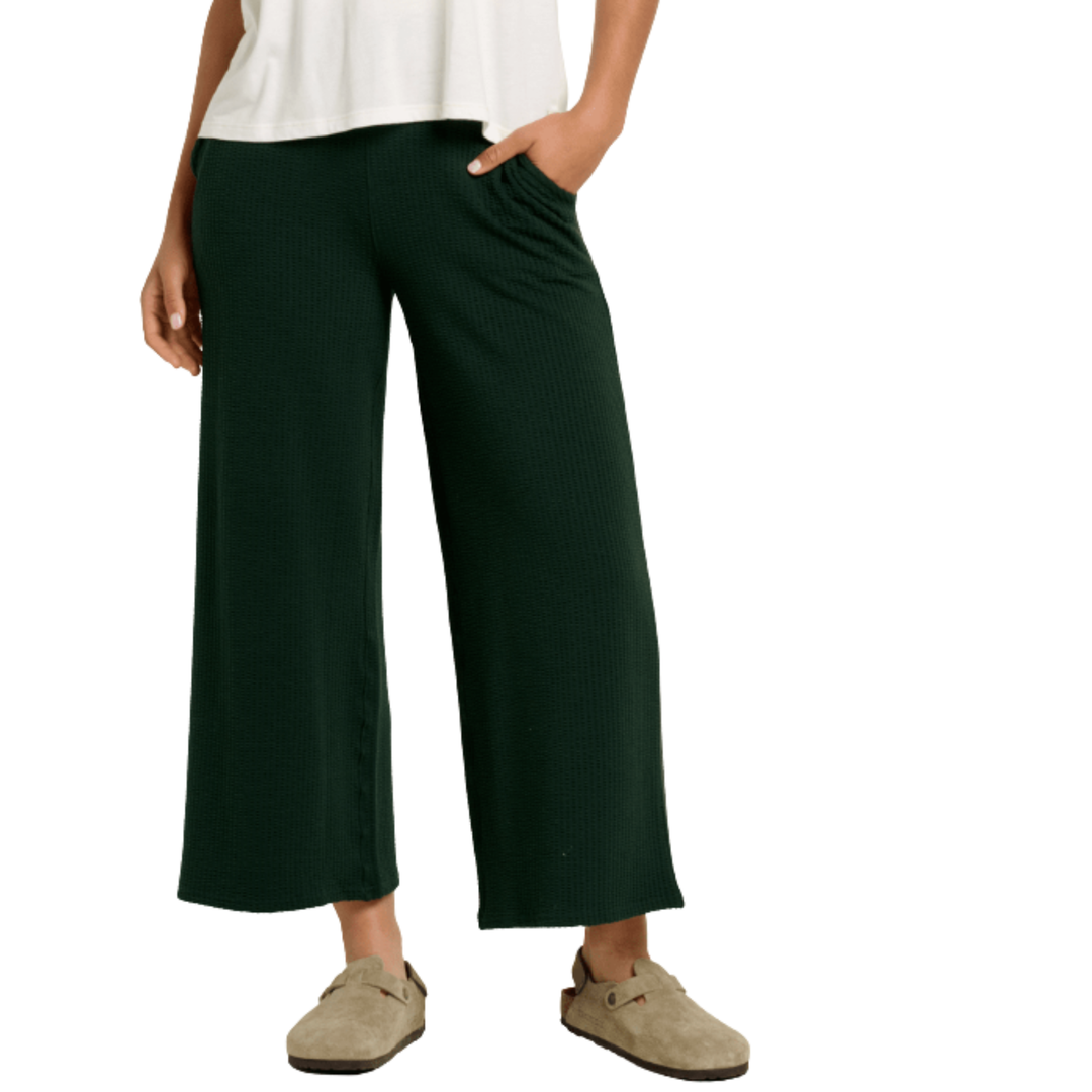 Person wearing dark green wide-leg pants on a white background