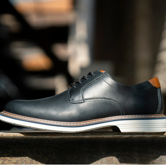 Black leather shoe with brown accents on a blurred background