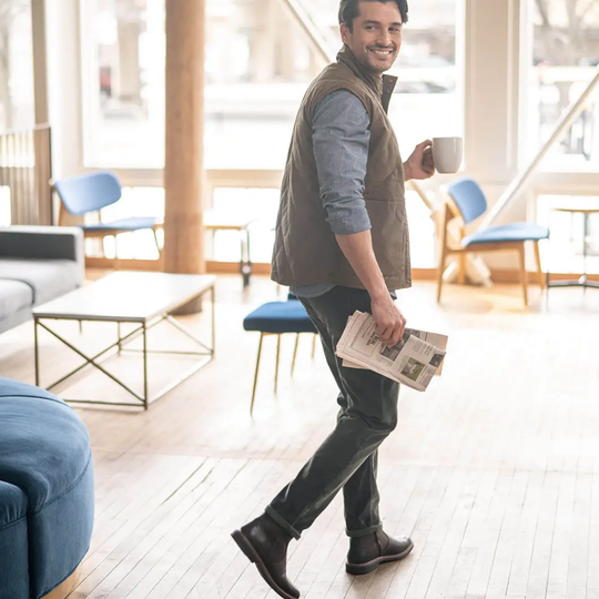 Man holding a newspaper and a mug in a modern living room