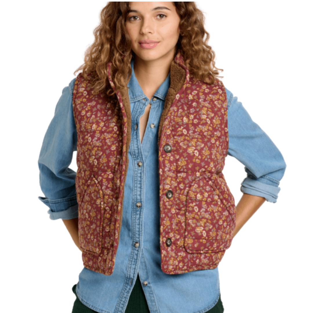 Woman wearing a floral patterned vest over a denim shirt on a white background