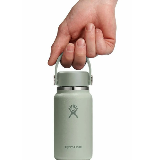 Hand holding a light green Hydro Flask water bottle on a white background
