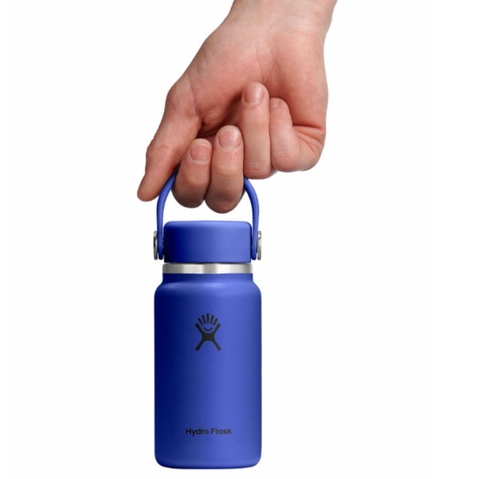 Blue Hydro Flask water bottle held by a hand on a white background