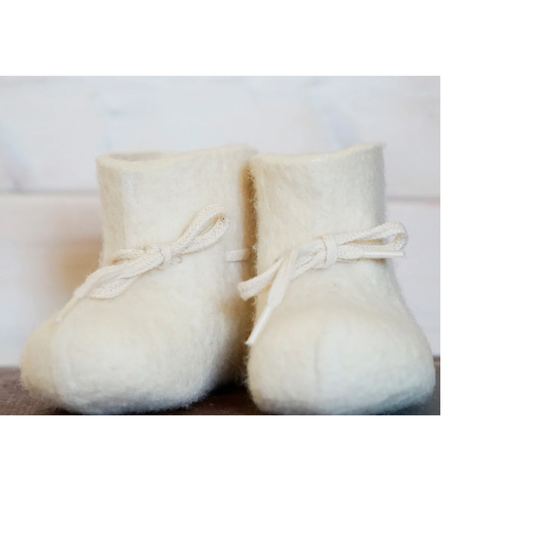 Pair of white baby booties with ribbons on a light background