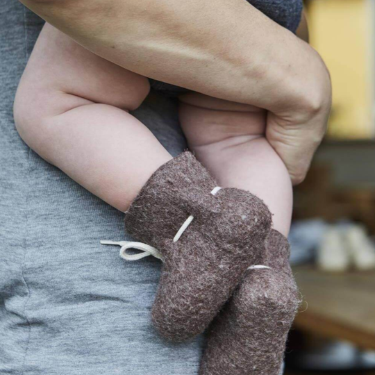 Close-up of a baby's foot wearing brown fuzzy booties 