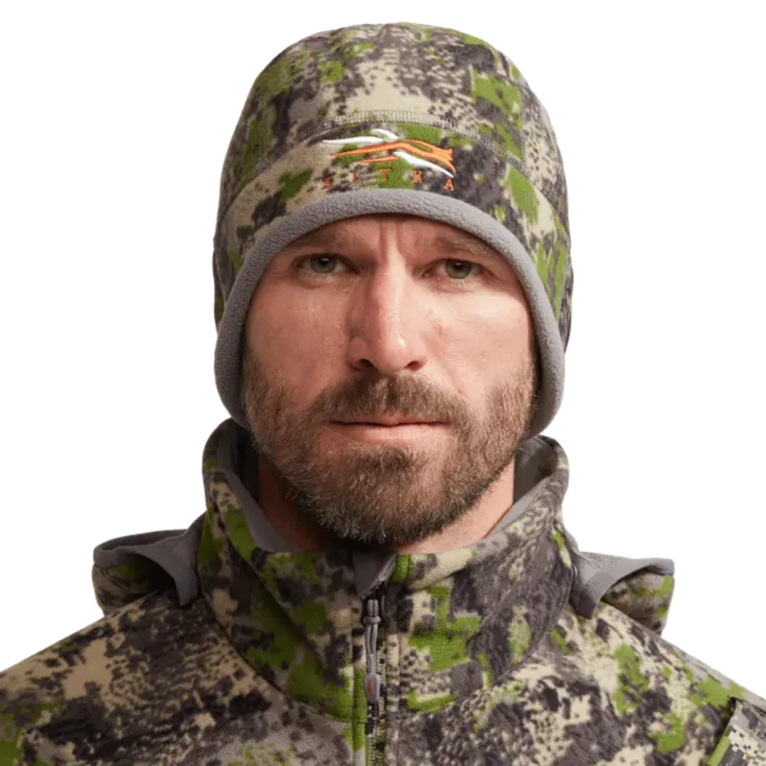 Man wearing a camouflage jacket and hat on a white background