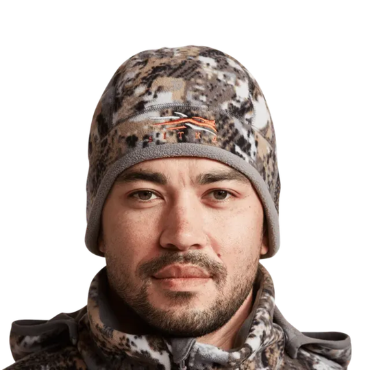 Man wearing a camouflage jacket and hat on a white background