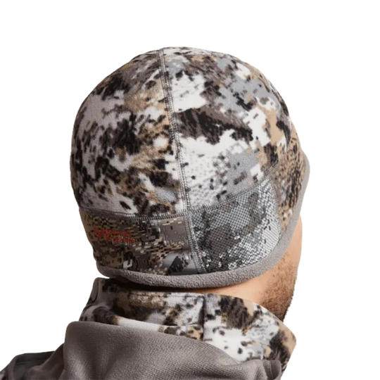 Camouflage beanie worn by a person on a white background