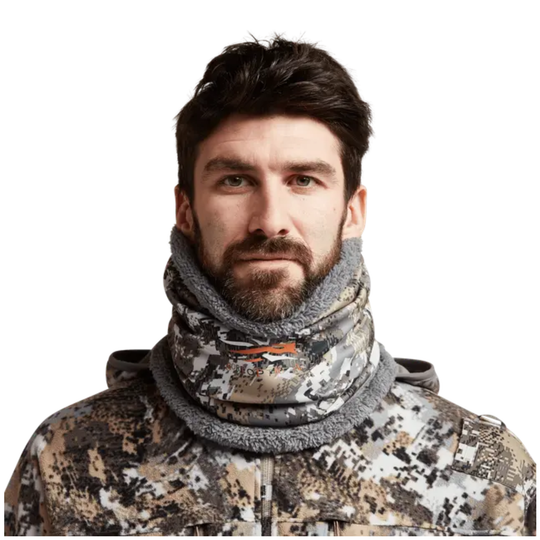 Man wearing a camouflage jacket and gray scarf on a white background
