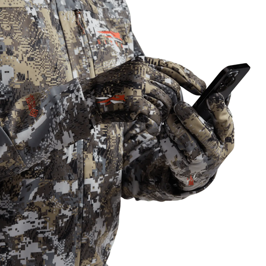 Person wearing camouflage hunting gear holding a phone.