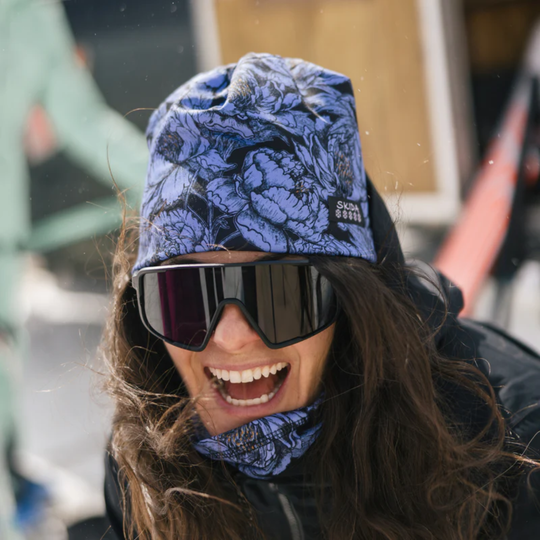 Person wearing a blue patterned beanie and goggles outdoors
