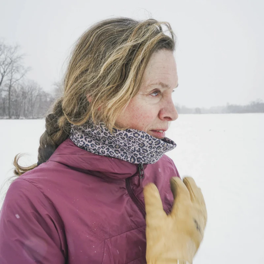 Woman wearing a purple jacket and patterned scarf in a snowy landscape