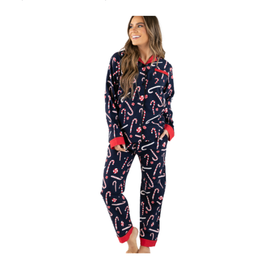 A woman modeling a navy blue holiday pajama set with a candy cane print and red trim, standing against a plain white background.