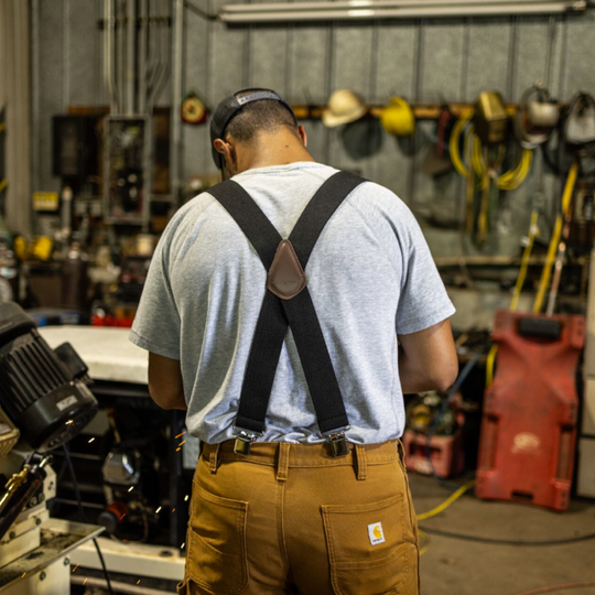 man wearing Carhartt Rugged Flex Elastic Suspenders - Black inside a garage with tools hanging up