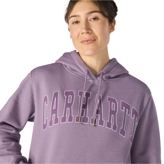 A woman wearing a lavender-purple Carhartt hoodie with 'CARHARTT' printed in arched varsity letters across the chest, shown against a plain white background.