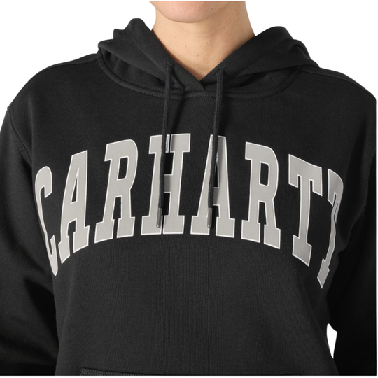 Woman wearing Carhartt Women's Marquette Varsity Sweatshirt - Black on a plain white background. Zoomed in Carhartt logo.