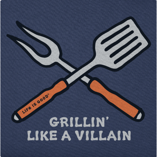 A close-up of a navy blue graphic print featuring crossed grill tools with orange handles and the text 'Life Is Good' and 'GRILLIN' LIKE A VILLAIN'.