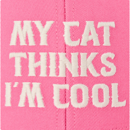 A close-up of a pink fabric item with white embroidered text reading 'MY CAT THINKS I'M COOL'.